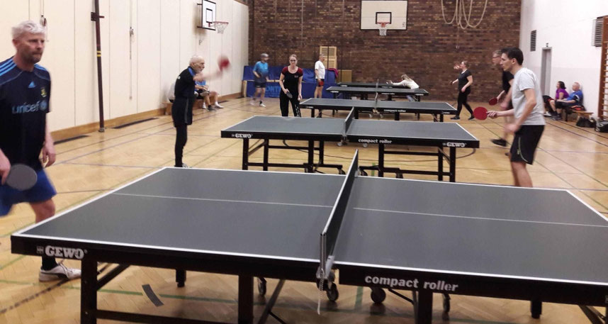Tischtennistische und Spieler in der Halle